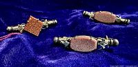 Front view of three antique nanny pins showing goldstone and copper lustre stone mounts on gold filled cylinders