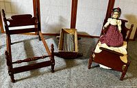 Photo showing two wooden doll beds and the pine cradle with padding on the ground.