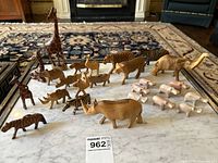 Group of 11 wooden African animal figurines including giraffes, zebras, elephant, cheetah, rhinoceros displayed on marble table