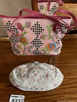 Birks vintage white beaded handbag with floral embroidery and pink beaded FF Roma handbag with floral and black diamond pattern side by side on wood surface.