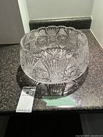 Top angle view of a clear, intricately patterned hand cut crystal bowl showing star and fan cut designs on sides and bottom.