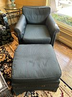 Front view of the down-filled armchair with matching ottoman in black and blue striped fabric upholstery.