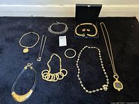 Overview image showing all jewelry pieces on black carpet including necklaces, bracelets, and boxed earring/bracelet set