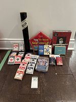 Full lot of assorted games and playing cards displayed on floor, including multiple decks of playing cards, box games, and domino tin.