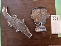 Photo showing both glass sculptures: owl and crocodile on a wooden surface