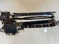 Image showing three different styles of Bugatti leather purses and five belts with various designs including studded and embroidered belts.