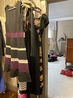 Four dresses hanging on a rack, showing variety of styles and colors including black with floral, and polka dot patterns.
