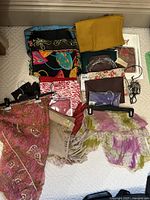 Photo of ladies scarves, leather gloves, travel cosmetic bags, eyeglass chains, and clutch bags arranged on carpeted floor.
