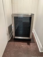 Wine fridge closed, showing glass door and stainless steel trim.