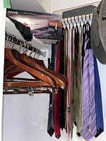 Photo showing multiple men's neckties hanging on a bar alongside wooden hangers and a digital tie rack box on top shelf