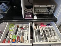 Overview of open kitchen drawers containing kitchen utensils, scissors, peelers, and flatware in organizers. Breville Mini Smart Oven on countertop above.