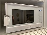 Front view of the Panasonic microwave showing the door window, digital display showing time 9:57, and control buttons.