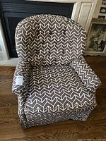 Front angled view of the accent armchair showing overall shape and chevron fabric pattern with armrests and skirted base.