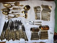 Overhead view showing knives, forks, spoons and serving pieces on white cloth