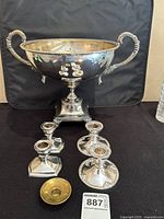Compote bowl, four candlestick holders, and brass ring arranged on black background