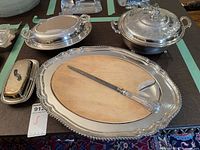 Overview of two covered vegetable dishes, covered butter dish, meat platter with wood insert and honing steel