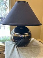 Front view of the table lamp showing the spherical black and chrome base and black fabric shade