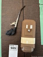 Vintage Asian pipe with elephant head clay bowl and intricately designed metal stem next to Michael Kors cigar holder in packaging.