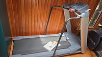 Full side view of the gray Trotter treadmill with digital console and manuals on the belt