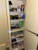 Full overview of shelf containing variety of candles and candle holders packed together