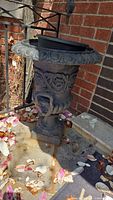 Full view of urn on pedestal base showing overall shape and rusted surface
