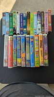 Image showing 19 assorted VHS tapes including children's movies and comedies with colorful, original VHS cases in upright position.