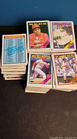 Stacks of unsorted baseball cards featuring various players and years. Cards show Reds, Twins, and Dodgers players prominently in front.