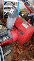 Photo of red Craftsman snow blower showing chute and front part, dusty with minor wear.