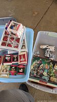 Overview of boxed Christmas ornaments and boxed Nativity set with loose figurines atop a plastic bin