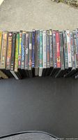 Photo shows a row of DVD cases laid out side by side on a black surface, angle showing titles of various movies and TV box sets.