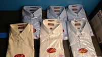 Full lot of six men's dress shirts by Arnie, new in packaging, varied colors and patterns.