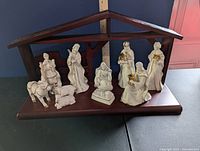 Front view of the full nativity set displayed within brown wooden stable. Includes Mary, Joseph, shepherd, wise men, animals, and baby Jesus figure.