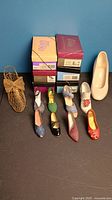 Photo showing 9 miniature shoes in different styles and colors alongside 10 shoe boxes.