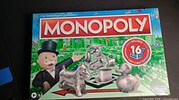 Front view of Monopoly board game box showing Mr. Monopoly and metal game tokens.