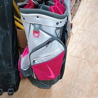 Front and sides of Nike women's golf bag showing zippered pockets, cushioned club dividers, and pink Nike swoosh logos