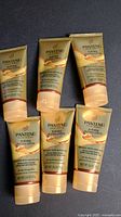 Six tubes of Pantene Gold Series Hydrating Butter-Crème shampoo arranged on a dark surface.