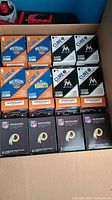 Photo of 52 boxes of sports team bandages stacked in a box: Denver Nuggets (orange and blue), Miami Marlins (black and white), Washington Redskins (football-textured boxes)