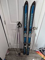 Pair of Rossignol skis standing upright with two ski poles beside them, showing overall lot contents.