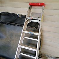 Image showing the Werner 6-foot aluminum step ladder leaning against a wall, with visible six steps and a red top cap.