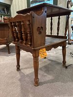 Side view of one wooden Ethan Allen end table showing spindle magazine holder and turned legs, with clover cut-out on side panel