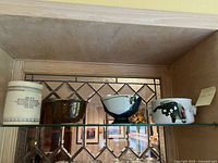 Four pottery bowls on a glass shelf showcasing their varying styles and sizes