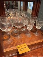 Four vintage Orrefors Illusion red wine glasses arranged on a wooden surface in front of a mirror, showing their shape and faceted design.