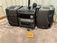 Full view of Aiwa NSX-V8000 main unit flanked by two speakers and remote on top, showing front panel details and connections.