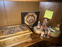 Two wood carved music boxes, catalog and assorted figurines on shelf