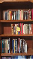Bookshelf with assorted hardcover and paperback books including war, aircraft, and classics