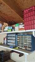 Shelf in garage with plastic drawer organizers and boxes containing assorted small hardware items like nails, screws, washers