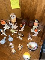 Top view of multiple bird and egg figurines arranged on a wooden shelf including owl, robins, small birds, and decorative eggs