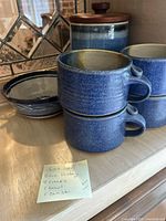 Photo showing the set of 4 blue crock bowls stacked with handles, a blue pottery canister with wooden lid, and one blue bowl. Sticky note confirms contents: 4 crocks, 1 bowl, 1 canister.