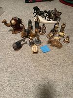 Full nativity set on carpet including various ceramic figures of Mary, Joseph, baby Jesus, Wise Men, shepherds, camels, sheep, and other animals.