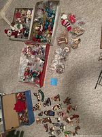 Top view of assorted Christmas ornaments spread on the floor including baubles, figurines, and a decorative bow.